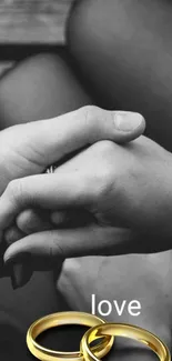 Couple holding hands with love text and golden rings.