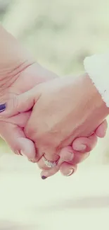 Romantic scene of two hands gently holding against a natural blurred backdrop.