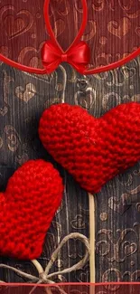 Knitted red hearts on textured brown background.