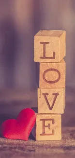 Wooden blocks spelling love with red heart on brown background.