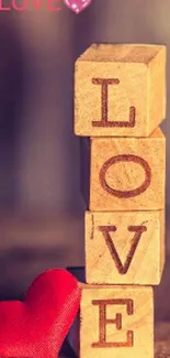 Wooden blocks spelling LOVE with a red heart on a brown background.