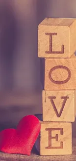 Wooden blocks spelling LOVE with a red heart in soft focus.