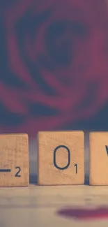 Scrabble tiles spelling LOVE with a blurred rose background.