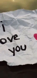 Crumpled note with 'I love you' and heart design.