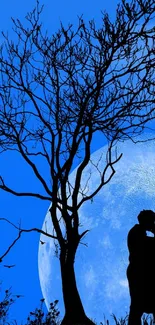 Silhouette of embracing couple under a tree with blue moonlit sky.