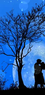 Silhouette of a couple against a blue moonlit sky with a tree in the foreground.