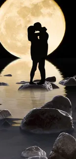 Couple silhouette against full moon on rocky path.