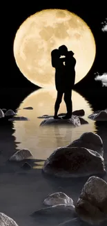 Silhouette couple under full moon on a rocky shoreline.