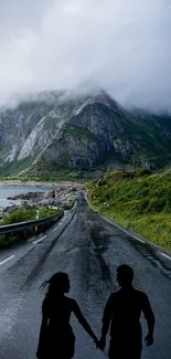 Couple holding hands on a foggy mountain road.