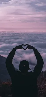 Silhouette forming heart at sunset over mountain background.