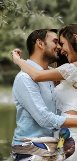 Romantic couple embrace by a lake with a duck.