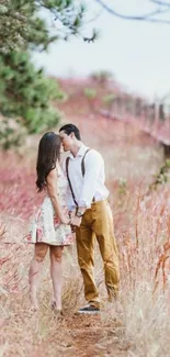 Romantic couple walking in pink grass field.