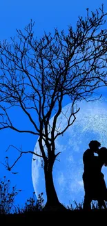 Silhouette of a couple kissing under a blue moonlit sky with a tree in the foreground.