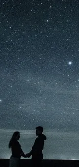 Silhouetted couple under starry night sky.