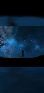 Silhouette of couple under starry night sky with tree on dark blue wallpaper.