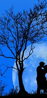 Silhouette of a couple kissing under a tree against a blue moonlit sky.