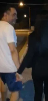 Couple holding hands during a nighttime stroll.