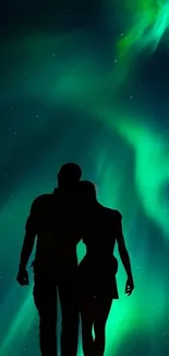 Silhouette of couple under vibrant Northern Lights display.