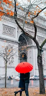 Couple in Paris with red umbrella and Arc de Triomphe in autumn.