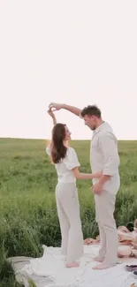 Romantic couple dancing in a meadow during a picnic at sunset.