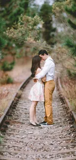 Couple embracing on a forest railway track.
