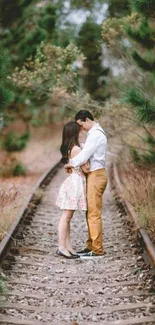 Couple embracing on a lush railway track amidst nature's serene setting.