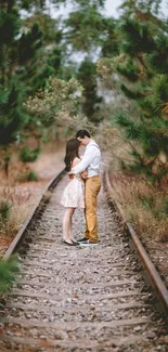 Romantic couple embracing on railway surrounded by lush green forest.