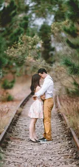 Couple embracing on railway track, surrounded by greenery.