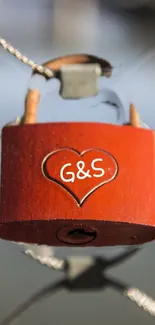 A close-up of a red heart-shaped lock on a bridge cable in sunlight.