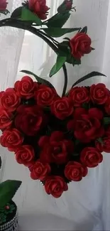 Heart-shaped arrangement of red roses with vibrant green leaves.