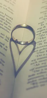 Romantic heart-shaped shadow with ring on a book page wallpaper.