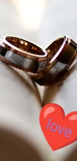 Wedding rings on an open book with a heart symbol on a mobile wallpaper.