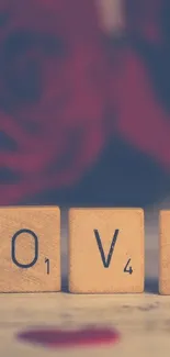 Scrabble tiles spelling 'LOVE' with a blurred red rose background.