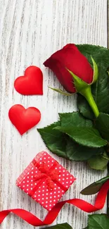 Romantic wallpaper with red roses, hearts, and a gift on wooden background.