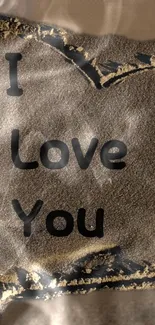 Romantic sand art wallpaper with 'I Love You' message in bold letters.