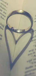 Ring casting heart shadow on open book pages.