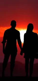 Silhouette of a couple against a vivid red sunset.