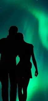 Silhouetted couple under vibrant aurora display.