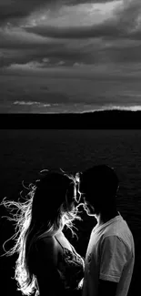 Romantic black and white silhouette of a couple by a lake at dusk.