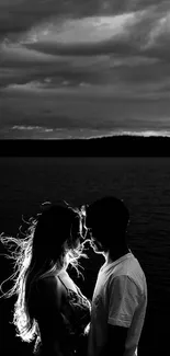 Black and white romantic silhouette of a couple by a tranquil lake.