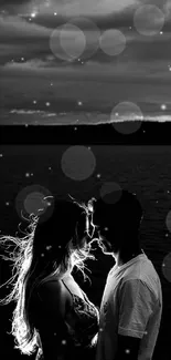 Black and white silhouetted couple by a tranquil lake at sunset.