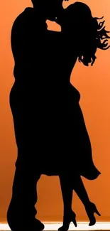 Silhouette of a romantic couple dancing against an orange background.