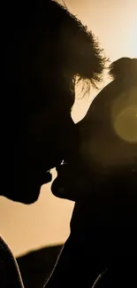 Silhouette of couple kissing at sunset with a golden glow.