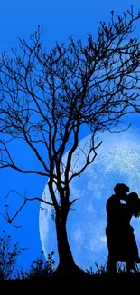 Silhouette of couple kissing under tree with full moon in blue night sky.