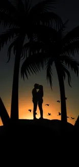 Silhouetted couple kissing at sunset among palm trees.