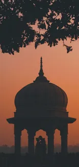 Silhouette of a couple under a dome against a sunset background.