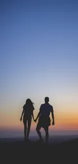 Silhouette of couple against colorful sunset sky, creating a romantic scene.