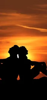 Silhouette of a couple against an orange sunset sky.