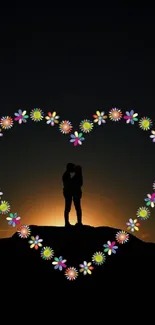 Silhouette couple framed by flower heart at sunset.