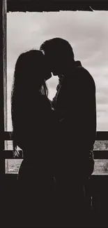 Silhouette of a couple kissing in front of a window.